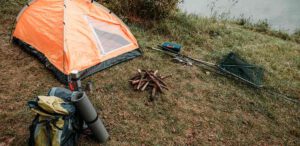 Zelt am Ufer mit Campingausrüstung